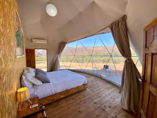 a bedroom with a bed and a large window at Ksar Shama - Atlas Mountain Retreat in Ouirgane