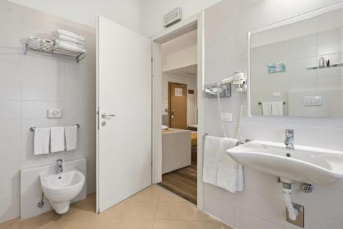 a bathroom with a sink and a toilet and a mirror at Hotel Regina in Bolzano