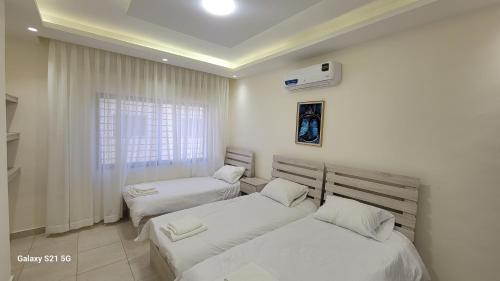 a bedroom with two beds and a window at #302 brand new two large bedrooms in Rujm ash Sharāʼirah