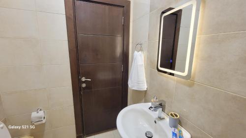 a bathroom with a sink and a wooden door at #302 brand new two large bedrooms in Rujm ash Sharāʼirah