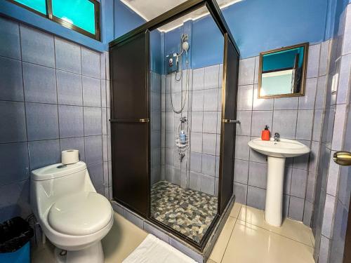 a bathroom with a shower and a toilet and a sink at Cabinas Arenal Home in Tanque