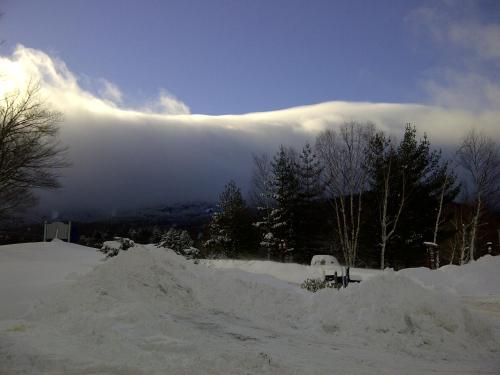 a storm cloud over a mountain with trees and snow at Cascades Lodge in Killington