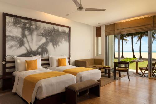 two beds in a hotel room with a palm tree mural at Jetwing Sea in Negombo