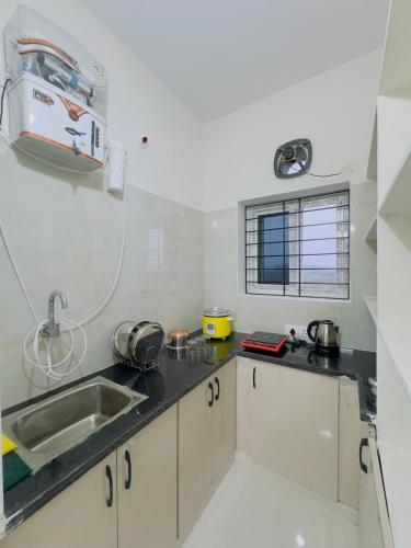 a kitchen with white cabinets and a sink and a window at B2 601 1BHK Flat by Charter Stays in Hyderabad