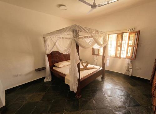a bedroom with a canopy bed and a window at Daystar Villa in Watamu