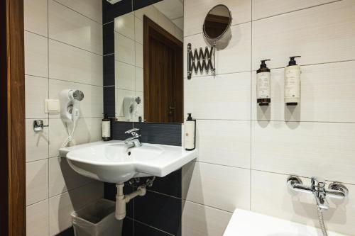 a white bathroom with a sink and a mirror at Focus Hotel Gdańsk in Gdańsk