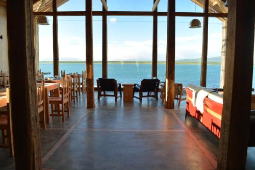 a dining room with chairs, tables, and a balcony at Hotel Simple Patagonia in Puerto Natales