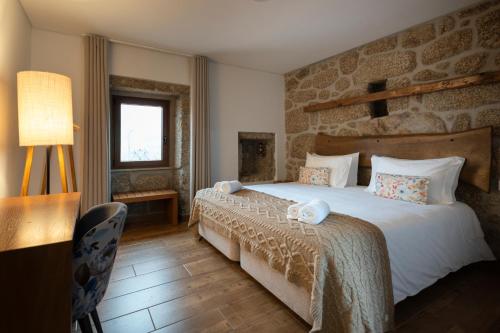 ein Schlafzimmer mit einem großen Bett und einer Steinwand in der Unterkunft Quinta do Limite - Agroturismo in Covilhã