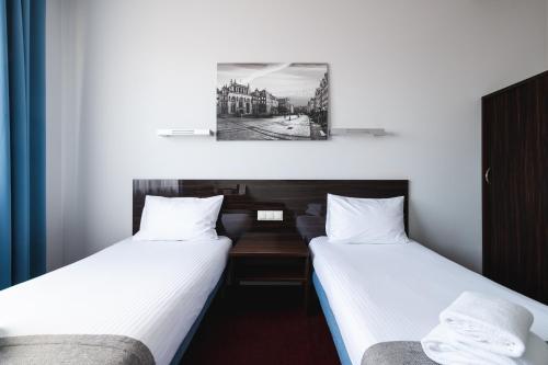 two beds in a room with white sheets at Focus Hotel Gdańsk in Gdańsk