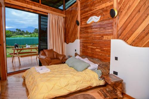 a bedroom with a bed and a chair on a deck at 2BR Forest Cabin, Jacuzzi, Fireplace & Mt Kenya Views in Naro Moru