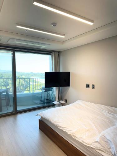 a bedroom with a bed and a flat screen tv at Yangyang Surfing Beach 18 in Saetchak