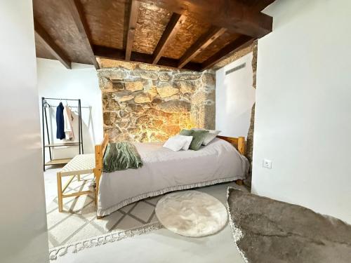 a bedroom with a bed and a stone wall at Casa do Oliveira - Gerês in Terras de Bouro