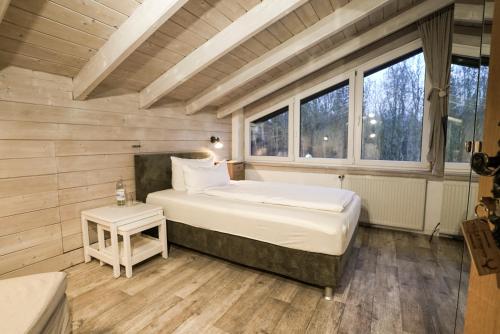 a bedroom with a bed in a room with windows at Landhotel Villa Foresta Braunlage in Braunlage