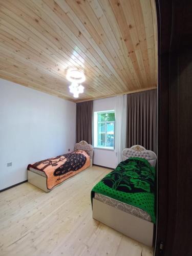 two beds in a room with a wooden ceiling at Naz in Lerik