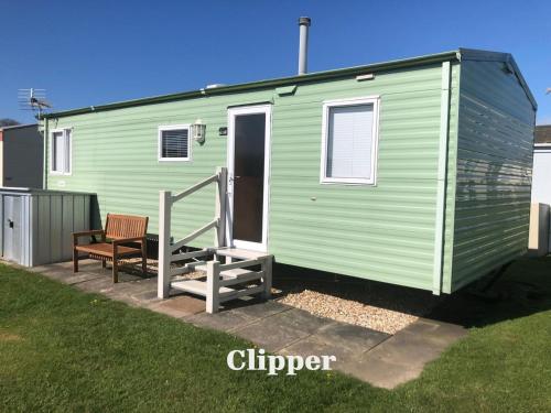 a green tiny house with a porch and a bench at Lincolnshire Sunrise Views in Mablethorpe
