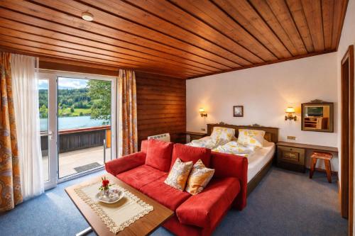 a hotel room with a bed and a red couch at Haus Kapeller in Seeboden