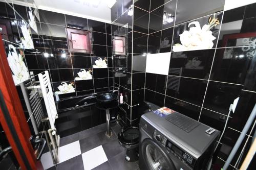 a black tiled bathroom with a washing machine in it at Ket Apartments in Galaţi