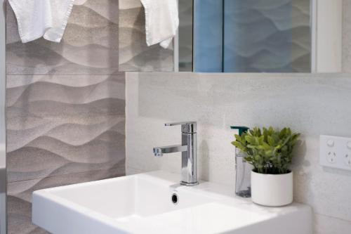 a bathroom sink with a faucet and a mirror at 1011 - First Light 2BR with Ocean Views - Prime Location in Newcastle