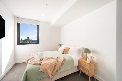 a white bedroom with a bed and a window at 1011 - First Light 2BR with Ocean Views - Prime Location in Newcastle