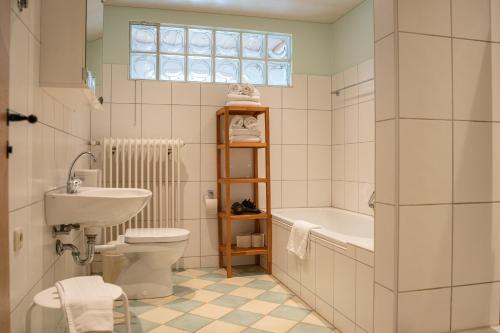 a bathroom with a sink and a toilet and a bath tub at Holzhauser Hof in Waldkraiburg