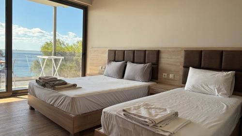 two beds in a bedroom with a view of the ocean at Coralli Apartments in Pefki