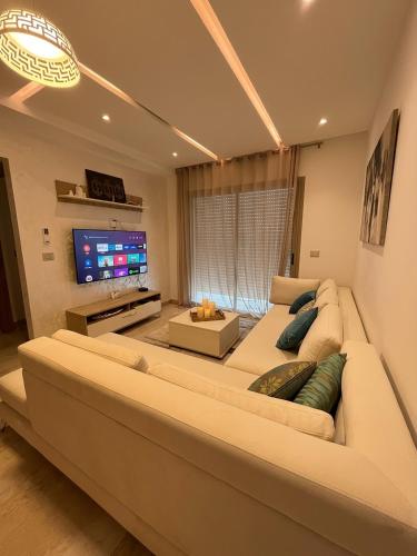 a living room with a large couch and a flat screen tv at Appt lux Hammamet Nabeul in Hammamet Nord