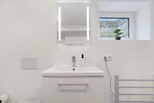 a white bathroom with a sink and a mirror at Ferienwohnungen Hirsch Schwarzwald in Bad Dürrheim