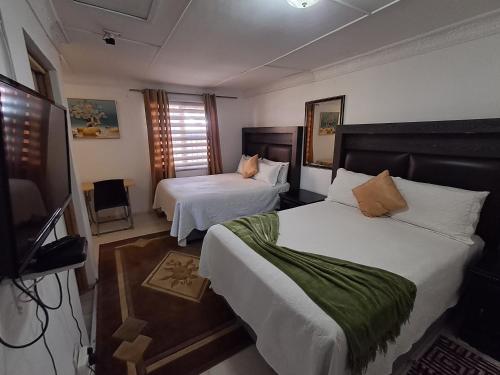 a hotel room with two beds and a flat screen tv at Emakhaya B&B in Mthatha