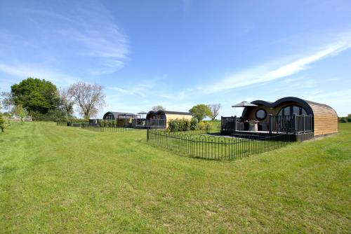 a small house in a field with a fence at Hollins Farm - Dog Friendly, Self Catering Holiday Lodges in Knaresborough