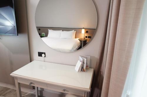a room with a bed and a mirror at Mercure Dartford Brands Hatch Hotel & Spa in Dartford