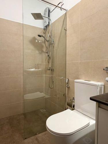 a bathroom with a toilet and a glass shower at Solar Airport Hotel in Seeduwa