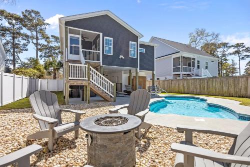 a home with a pool and chairs and a house at Pool Spa Fire Pit & More at this OKI Escape in Oak Island
