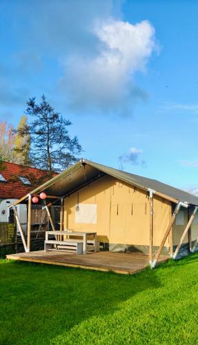 a large yellow house with a wooden deck at Glamping Safaritent 4 persoons in Hindeloopen