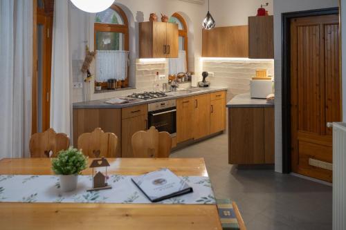 a kitchen with wooden cabinets and a wooden table with a dining room at Bolla Nyaralóház in Hegyhátszentjakab