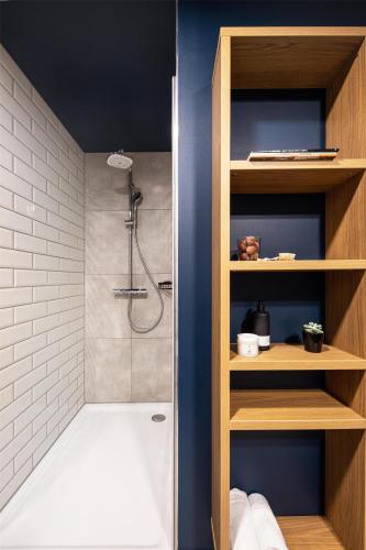 a bathroom with a shower with a white tile wall at ipartment Darmstadt HOME by Best Western in Darmstadt