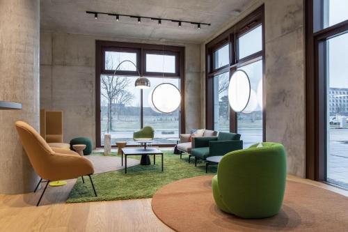 a living room with chairs and tables and windows at ipartment Berlin Airport HOME by Best Western in Schönefeld