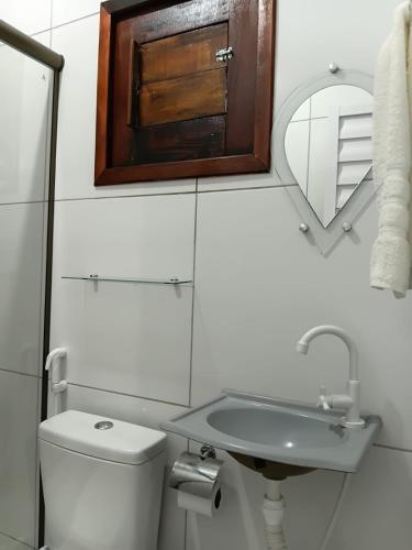 a bathroom with a toilet and a sink and a mirror at Suítes Maanaim Flecheiras in Flecheiras
