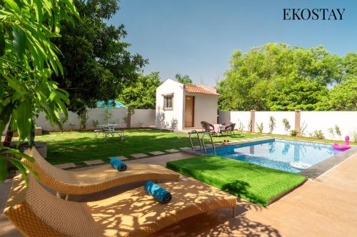 a backyard with a swimming pool and a house at EKOSTAY Gold - Vanamora Villa in Pandhurli