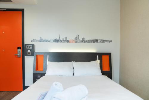 a bedroom with a large bed with an orange and white at easyHotel Ipswich in Ipswich