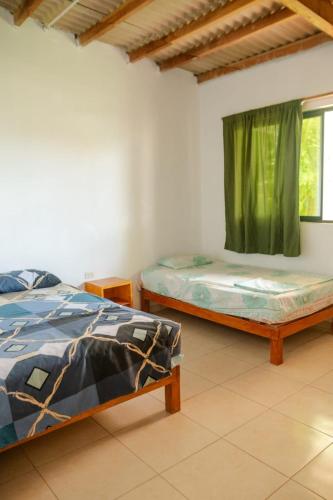 two beds in a room with a window at Dylan Beach in Zorritos