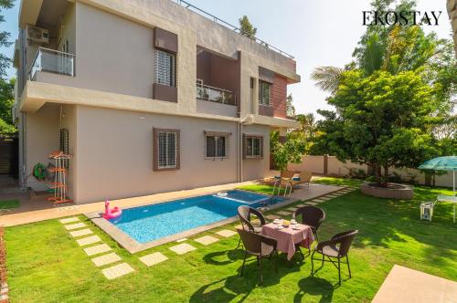 a backyard with a swimming pool and a house at EKOSTAY Gold - Vanamora Villa in Pandhurli