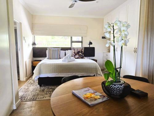 a bedroom with a bed and a table with a vase of flowers at Fairfax Studio in Nottingham Road