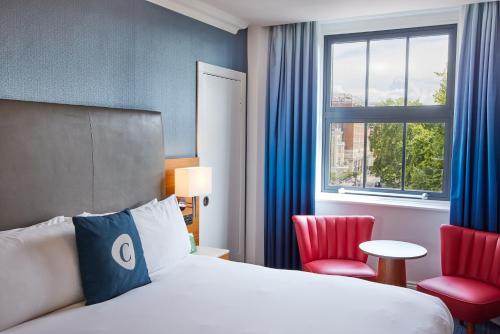 a hotel room with a bed and two red chairs at The Cumberland, London in London