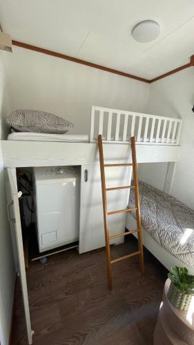 a bunk bed in a room with a ladder and a desk at Geniet van rust en privacy in onze gezellige chalet op familiecamping De Tien Heugten in Drenthe in Schoonloo