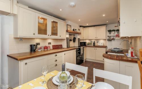 a kitchen with white cabinets and a table and chairs at 1 Apse Castle Cottage - Chocolate Box Cottage, Pet-Friendly 16th Century Cottage, surrounded by Ancient Woodland in Shanklin in Shanklin