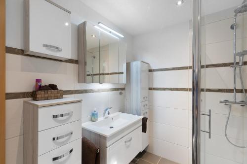 a white bathroom with a sink and a shower at Ferienwohnung Hochspessart in Rothenbuch