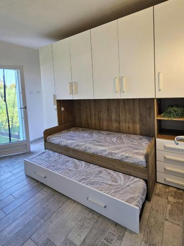 two beds in a room with white cabinets at Serendipity, La Caletta in La Caletta