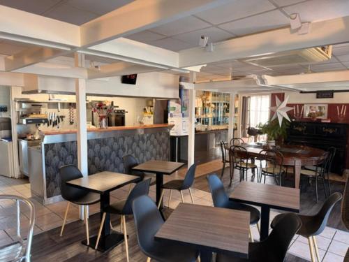 a restaurant with tables and chairs and a kitchen at Brit Hotel Essentiel Pau Lescar in Lescar