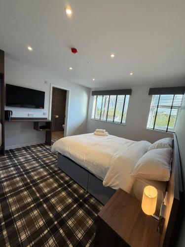 a bedroom with a large bed and a flat screen tv at Claremont Hotel in Alloa