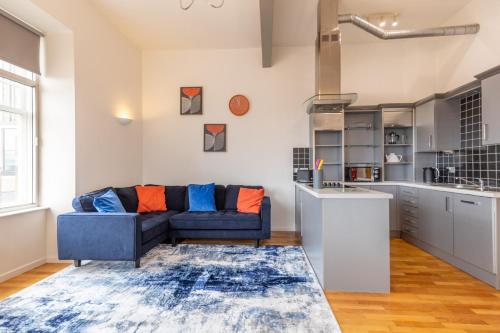 a living room with a blue couch and a kitchen at The Loft - Properties Unique in Newcastle upon Tyne